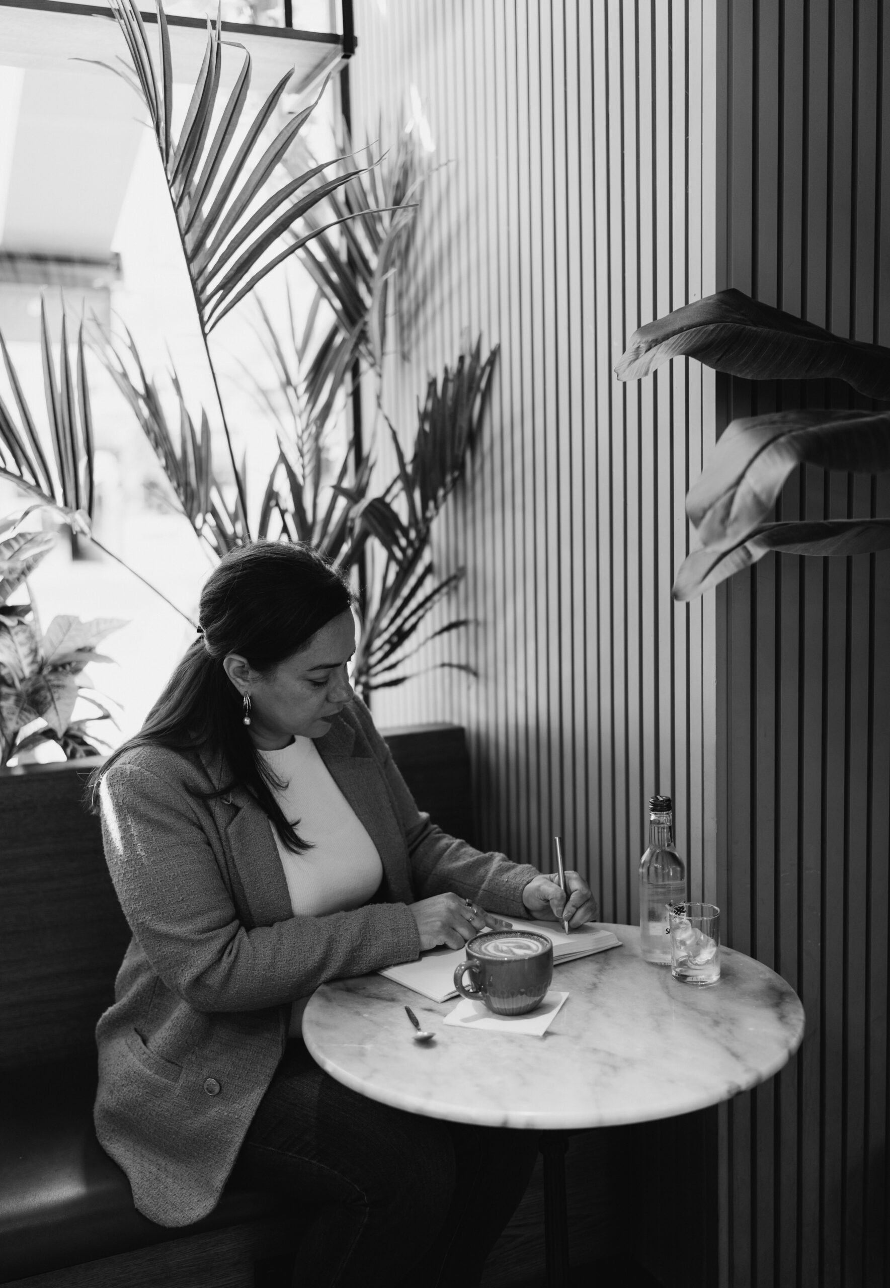 Woman writing notes at a café during a focused planning session